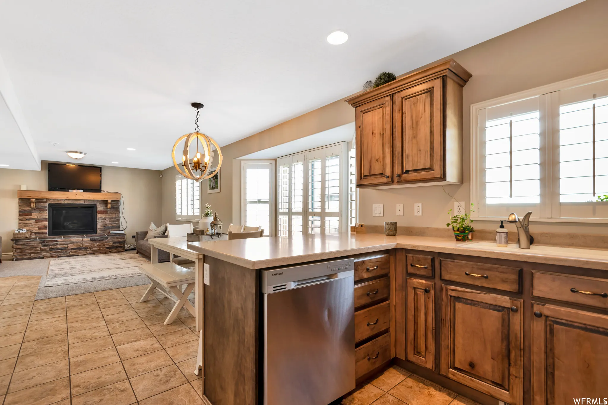 Kitchen with dishwasher, light tile patterned floors, open floor plan, wood finish cabinets, and a peninsula
