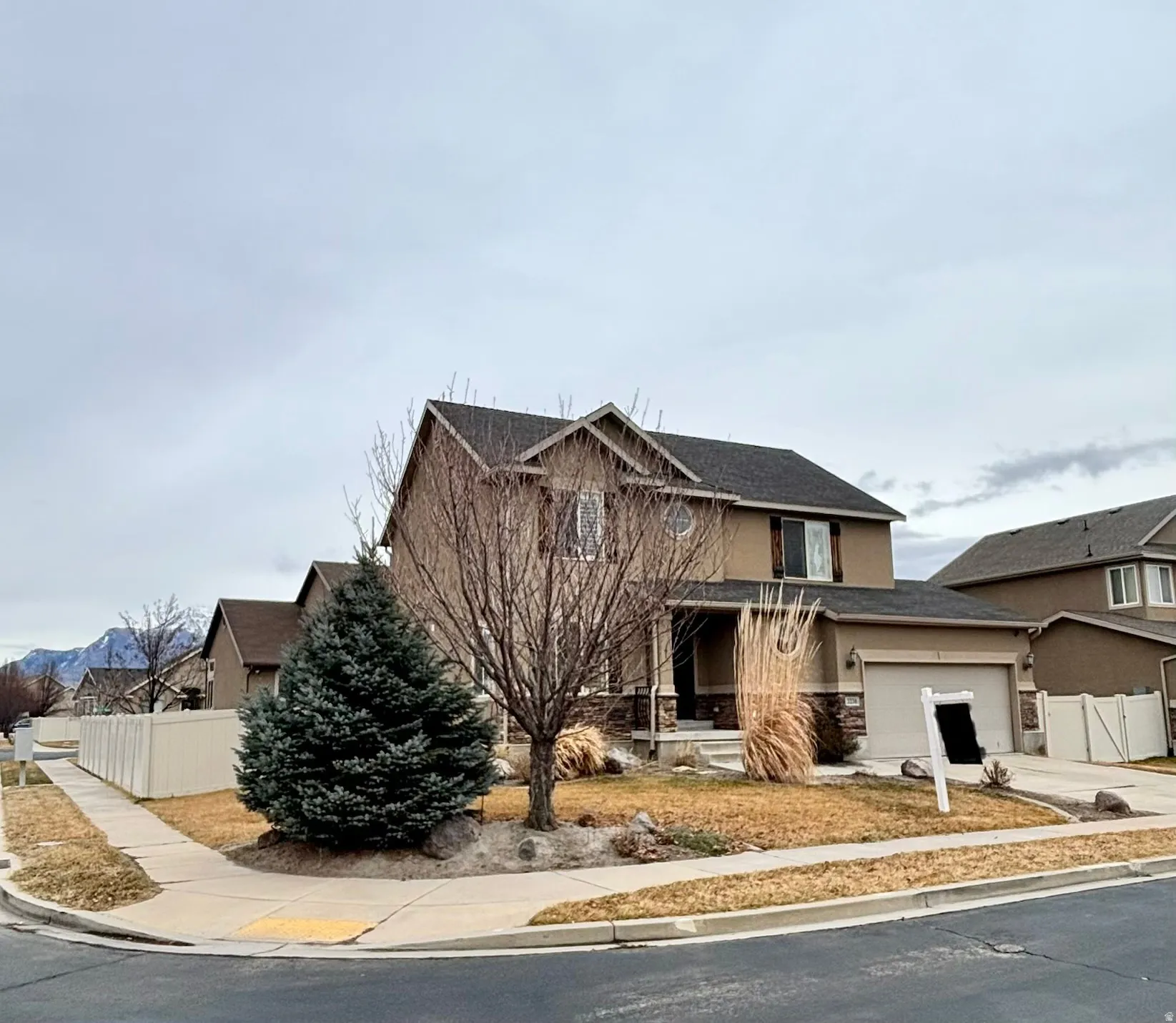 View of front of property with stucco siding, driveway, an attached garage, a porch, and a shingled roof