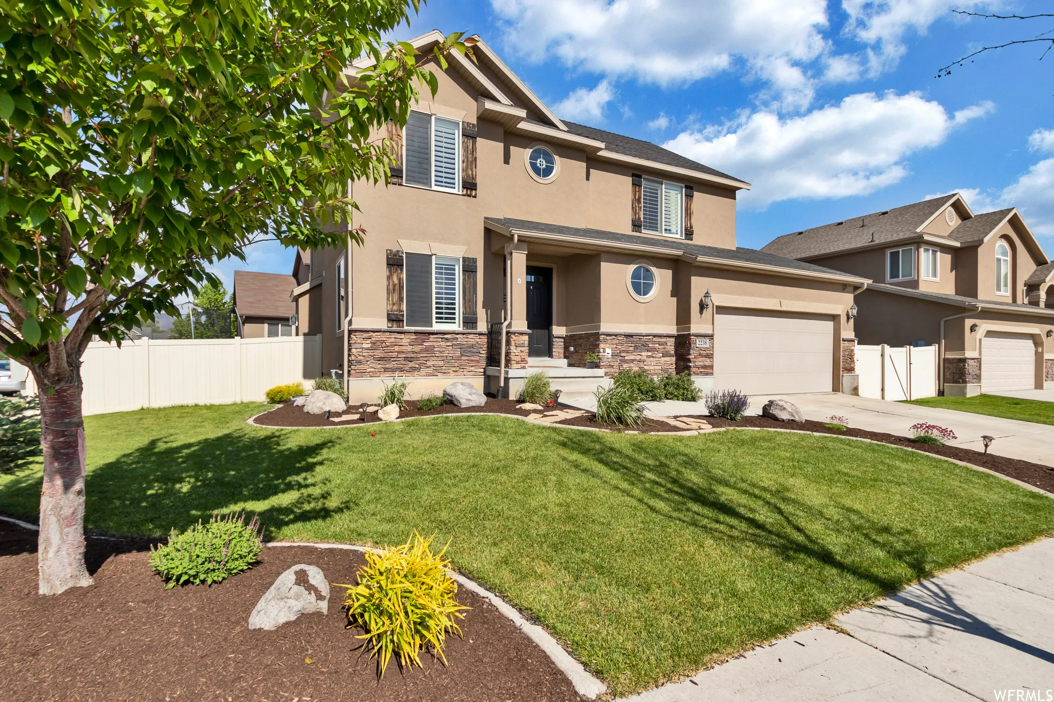 View of front of property with stucco siding, concrete driveway, and stone siding
