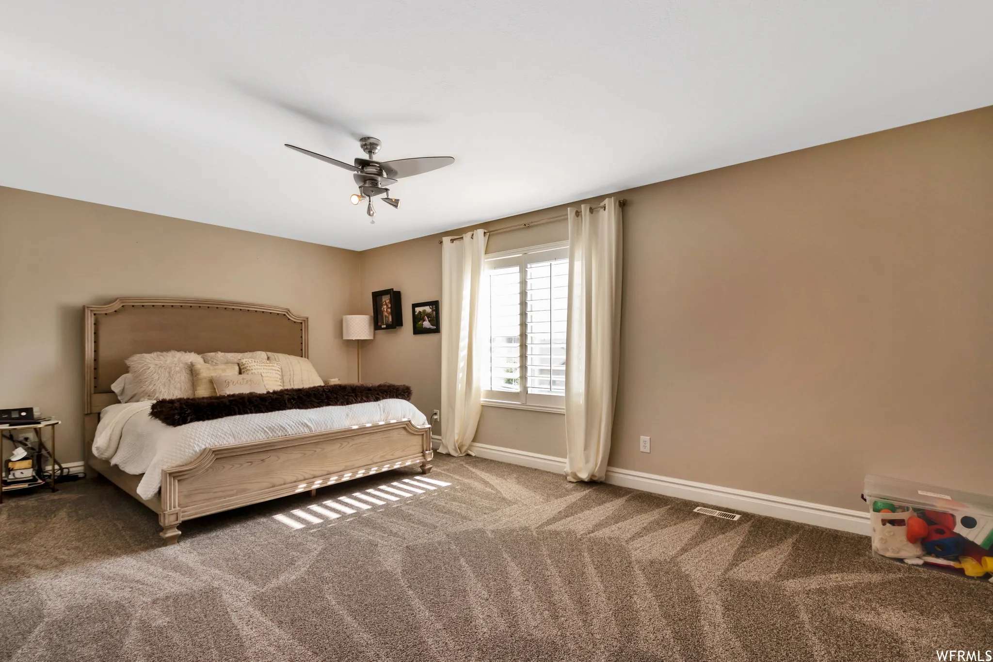 Carpeted bedroom with baseboards and a ceiling fan