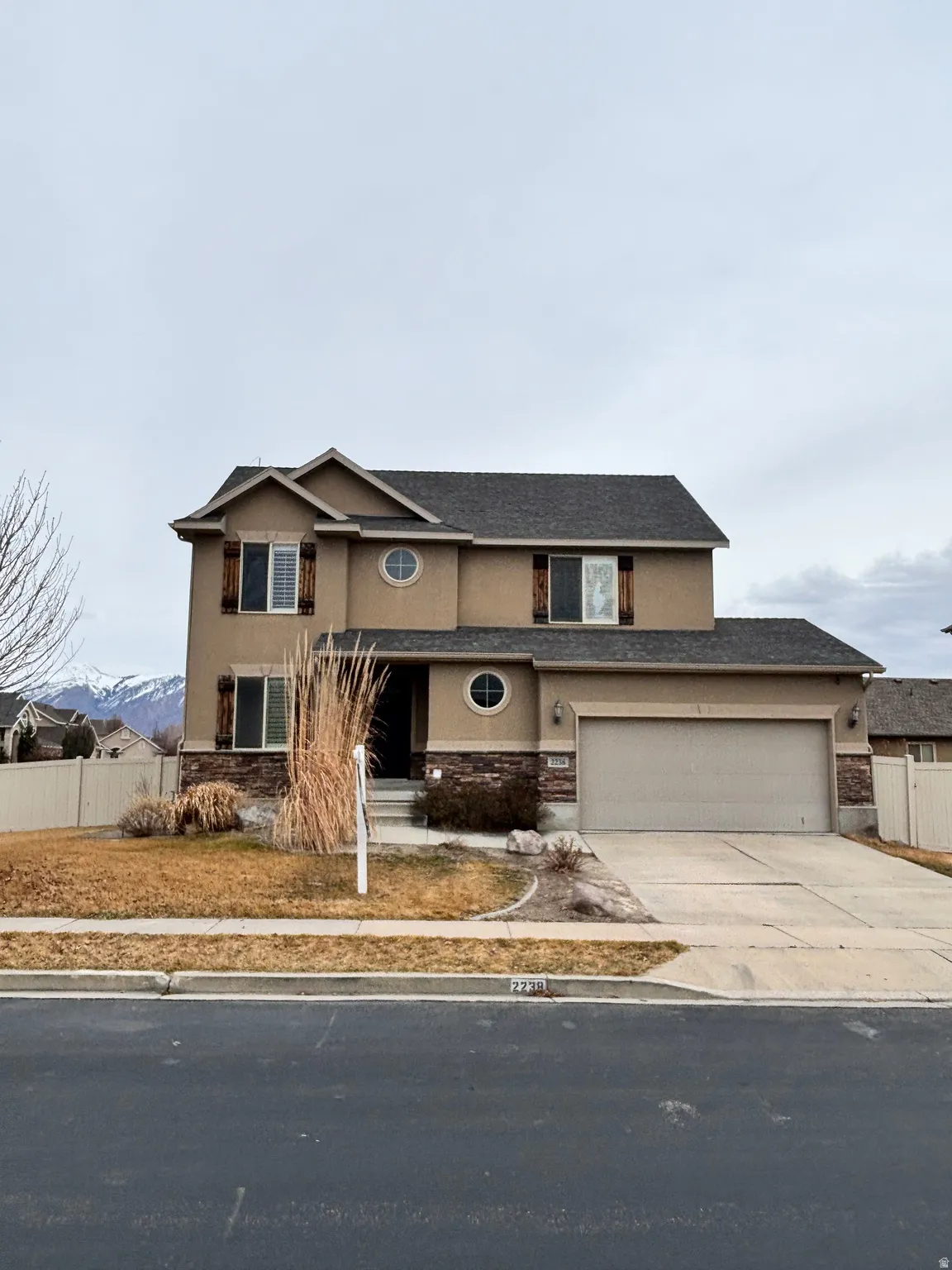 Traditional-style house featuring stucco siding, stone siding, concrete driveway, a garage, and roof with shingles