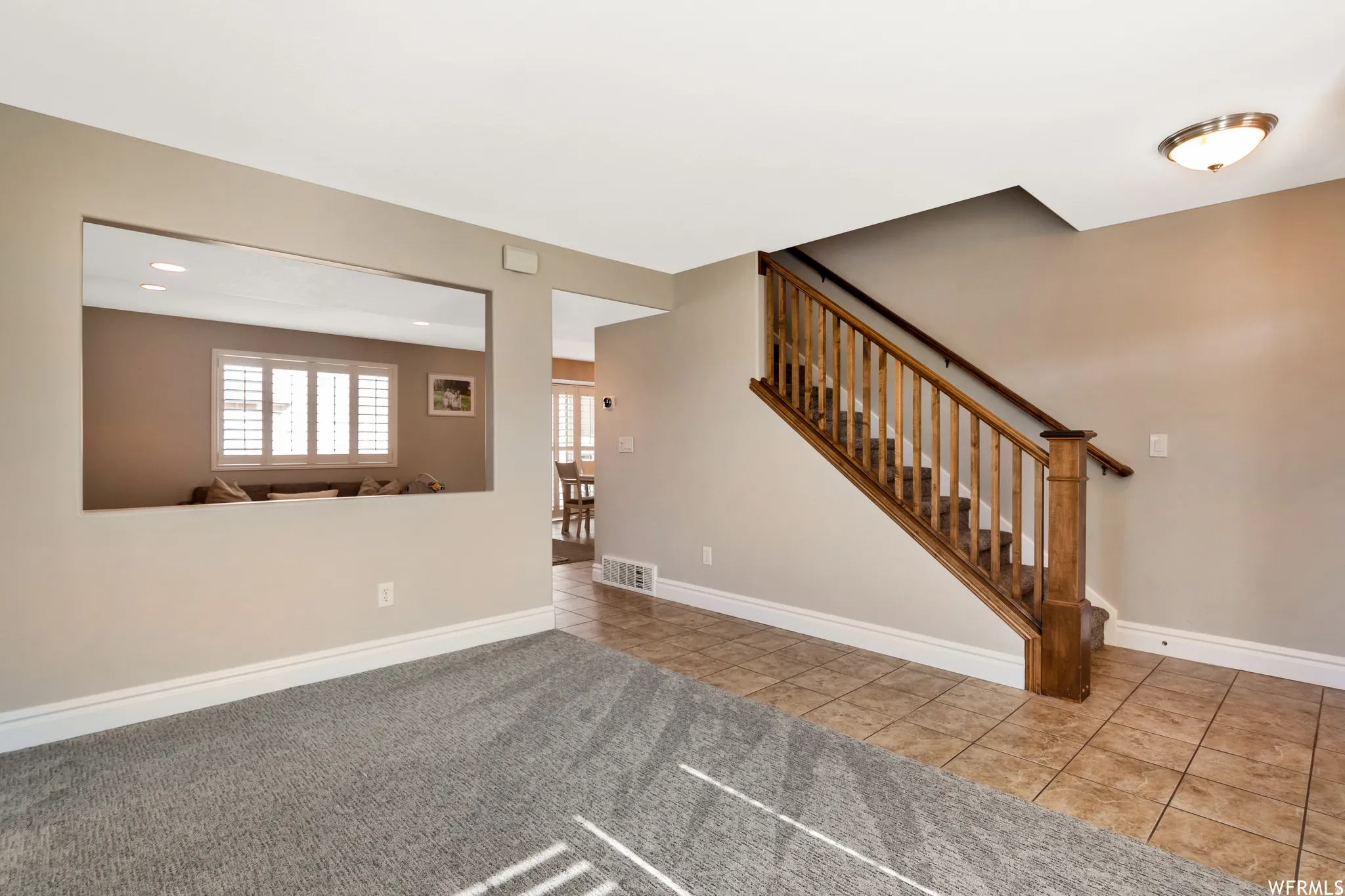 Unfurnished living room featuring stairs and tile patterned floors