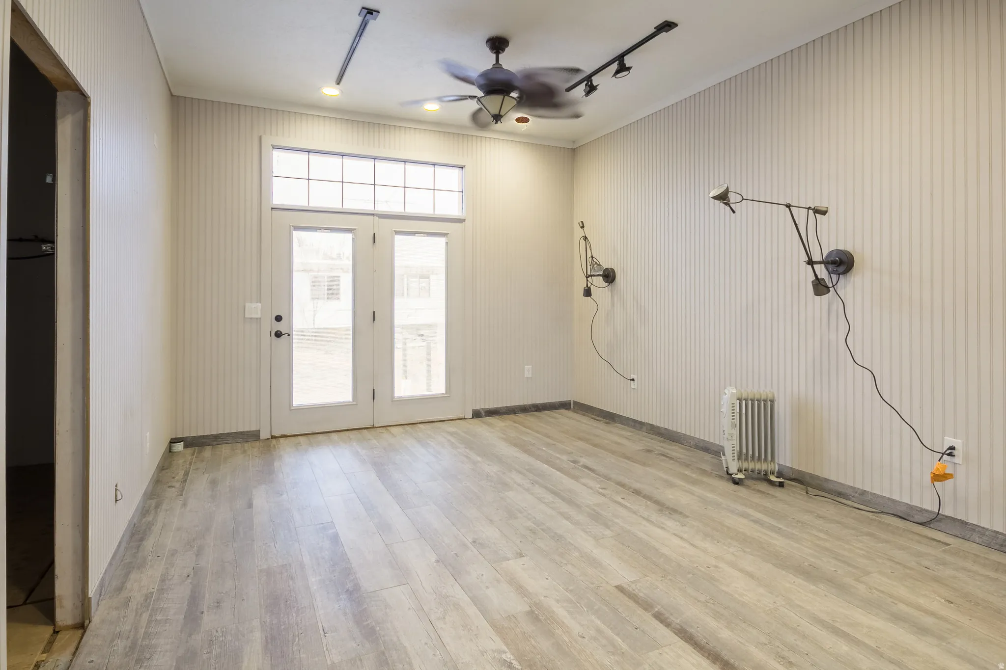 Entryway with light wood-style floors, ceiling fan, radiator, and rail lighting