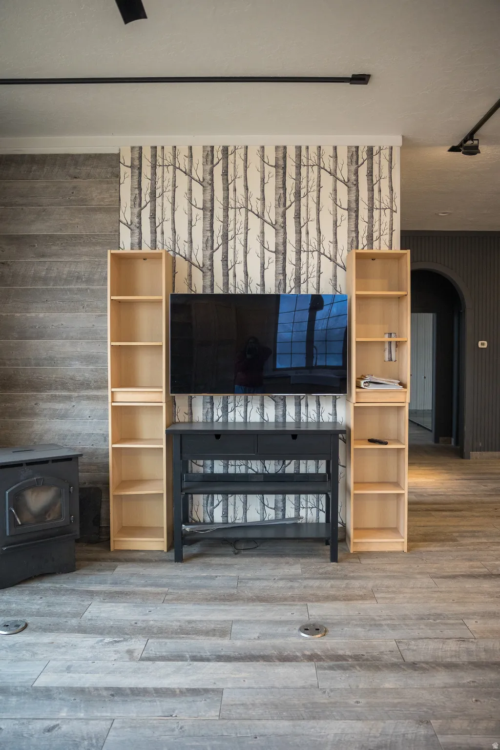 Detailed view of a wood stove, arched walkways, wood finished floors, and wooden walls