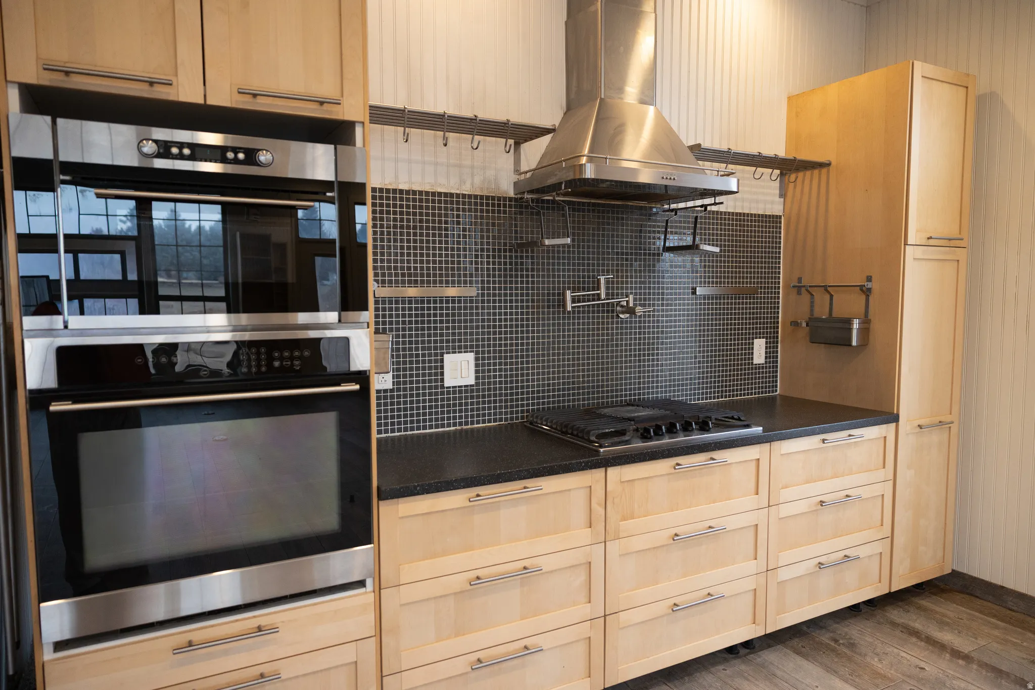 Kitchen featuring light wood finish cabinets, stainless steel appliances, island range hood, dark wood finished floors, and decorative backsplash