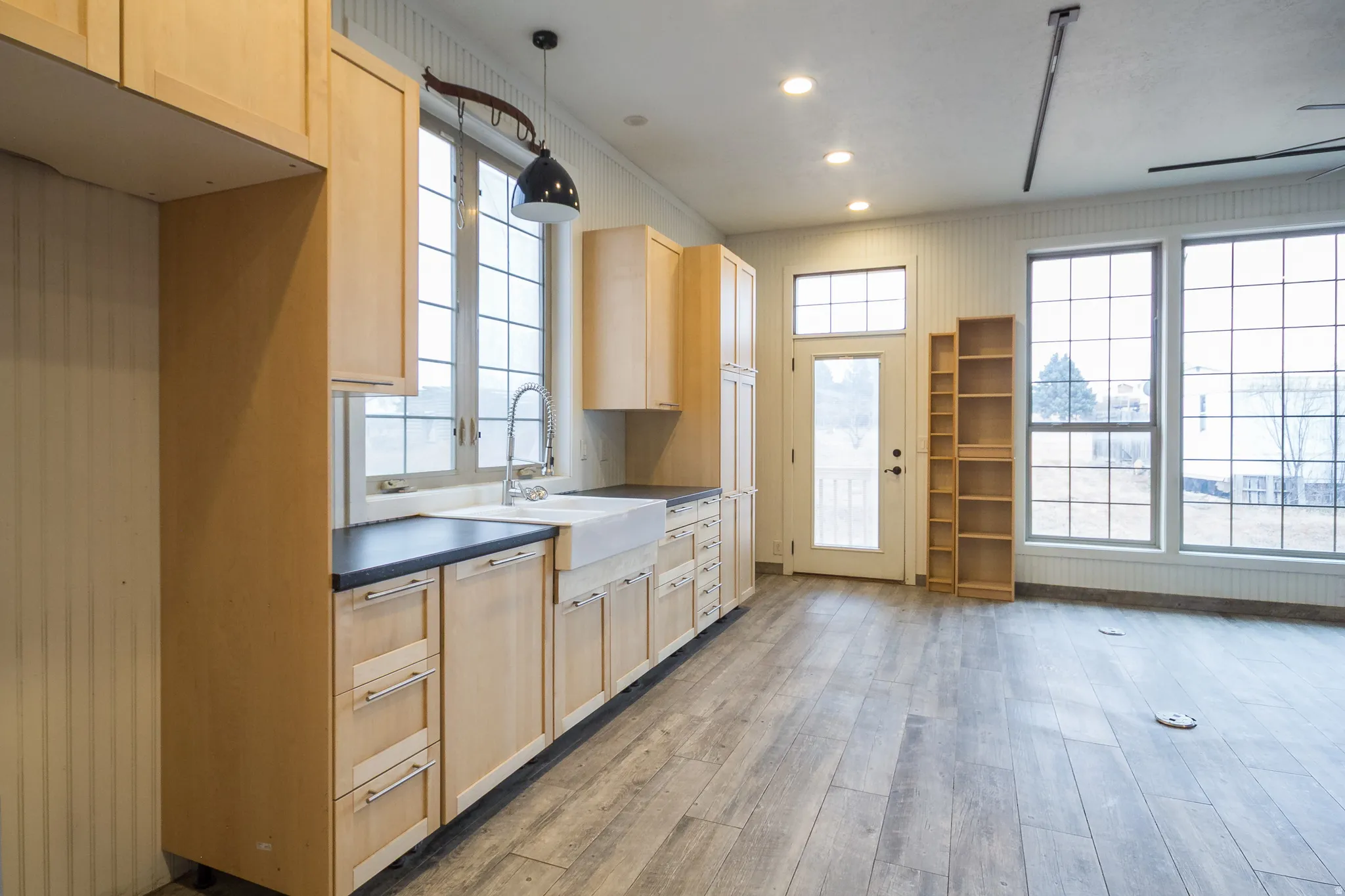 Kitchen featuring light wood finish cabinetry, dark countertops, light wood-type flooring, recessed lighting, and a ceiling fan