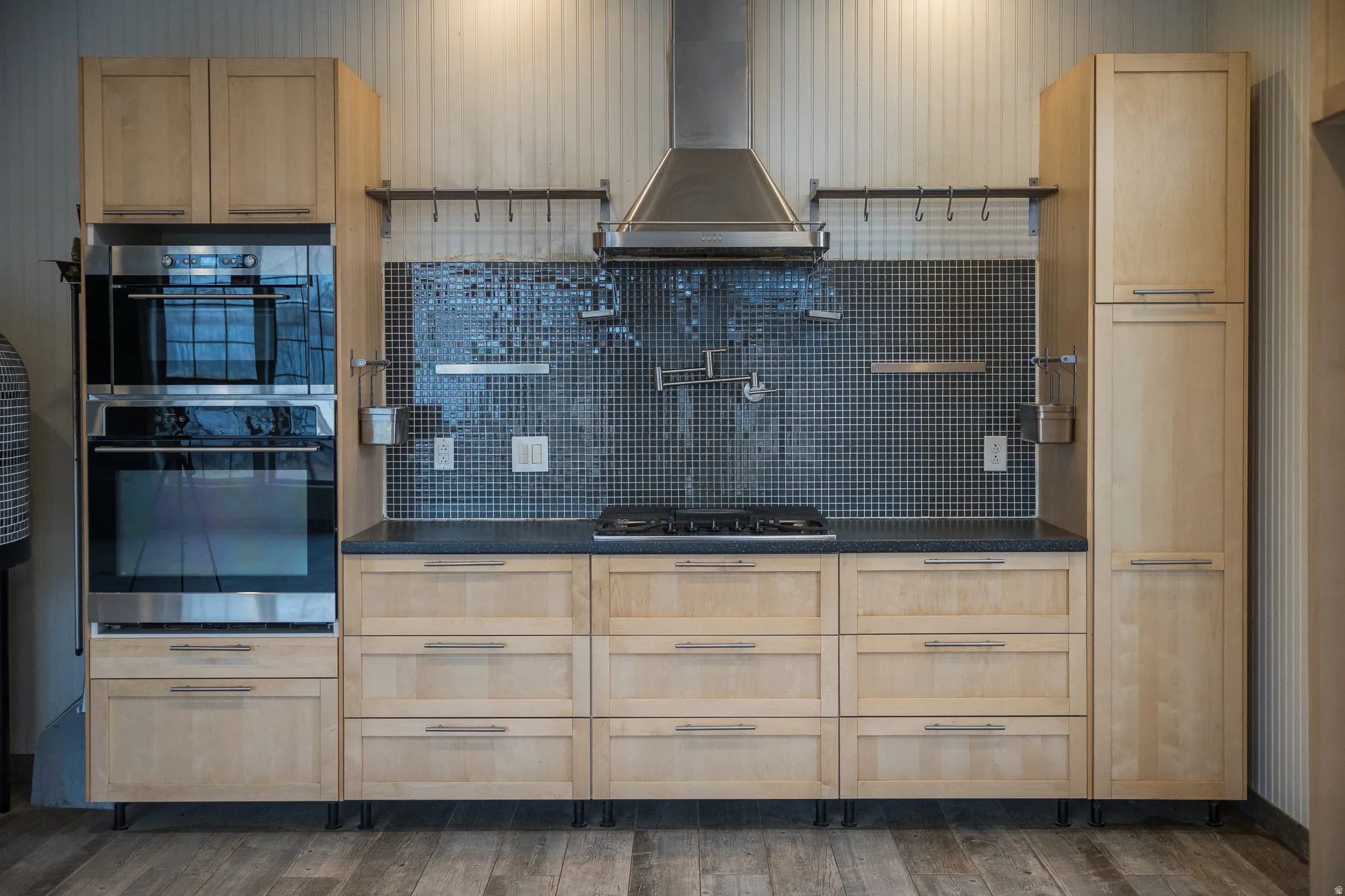 Kitchen featuring light wood finish cabinets, dark countertops, stainless steel appliances, and decorative backsplash