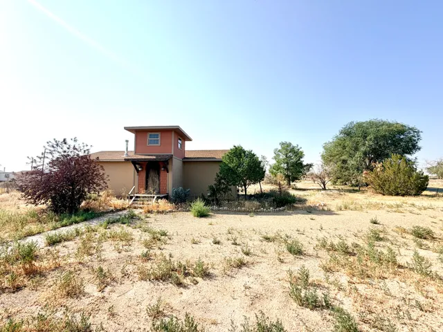 Entryway tower with an overhang, multiple mature trees, and a gravel pathway