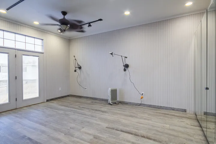 Primary bedroom, wood-style tile floors, ceiling fan, radiator heating unit, and rail lighting and recessed lighting