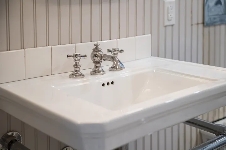 Bathroom view of tongue and grooved walls and a sink