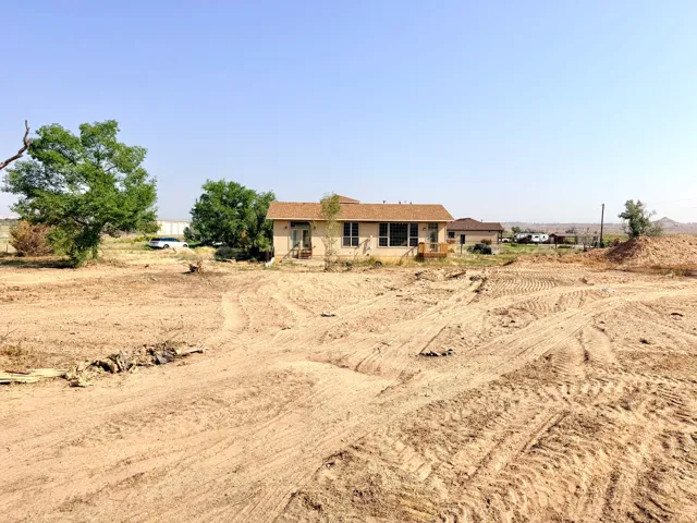 Expansive undeveloped lot with a single-story residence featuring a wood deck and multiple windows