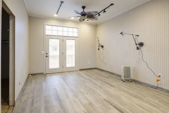 Primary bedroom, wood-style tile floors, ceiling fan, radiator heating unit, and rail lighting and recessed lighting