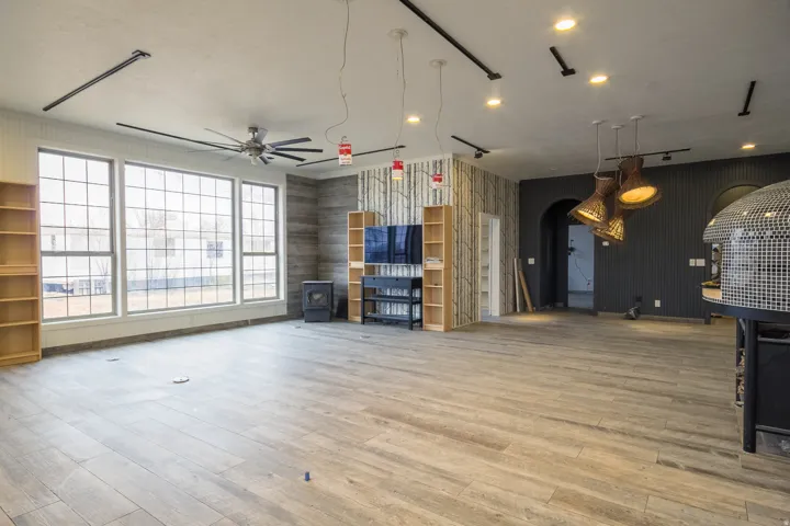 Living room with arched walkways, ceiling fan, and light wood-tile flooring