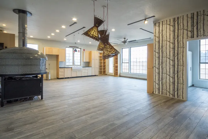 Kitchen featuring a ceiling fan, light wood tile floors, light wood finish cabinetry, and hanging light fixtures
