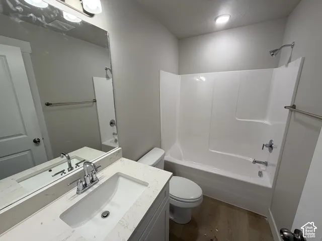 Bathroom featuring a vanity with an integrated sink, polished chrome faucet, white countertop, and a shower/tub combination with a white surround