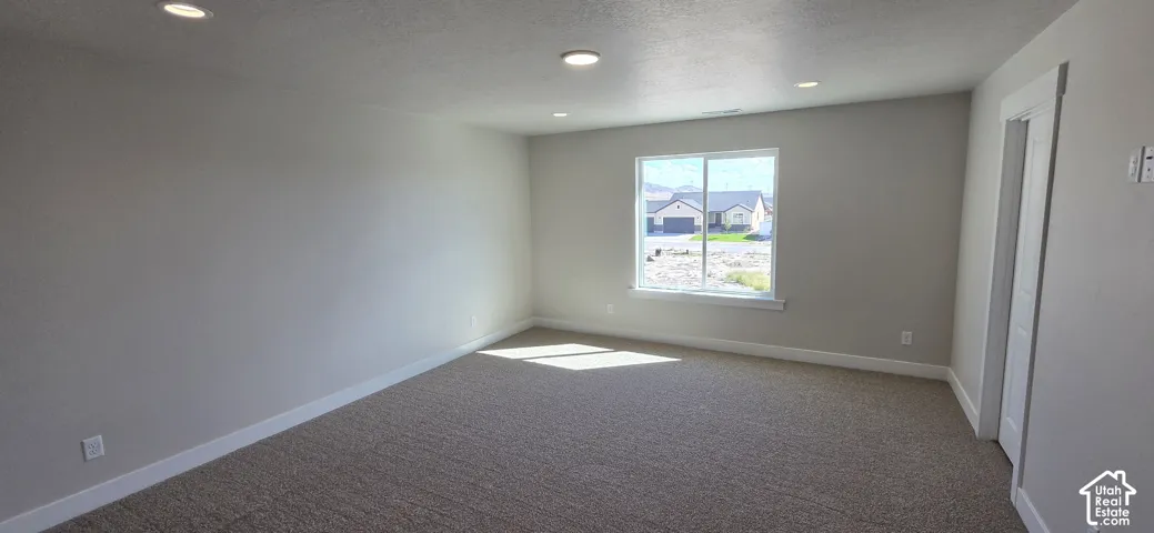 Recessed ceiling lighting, neutral wall tones, carpeted flooring, and a white-trimmed window