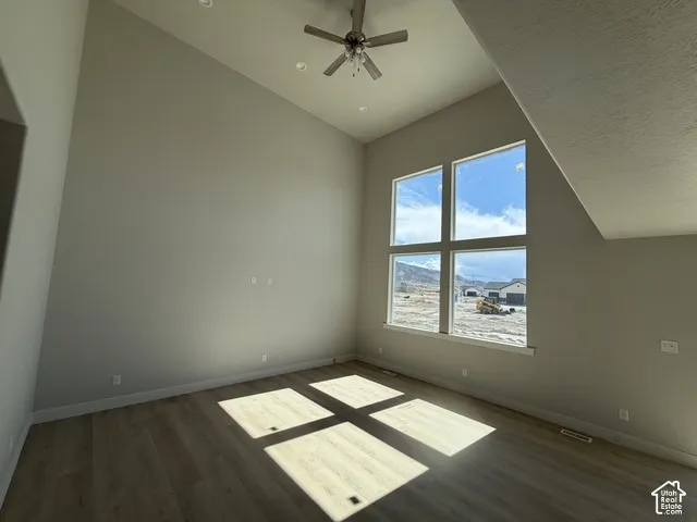 Vaulted ceiling with a ceiling fan, recessed lighting, large multi-pane windows, and wood-finish flooring