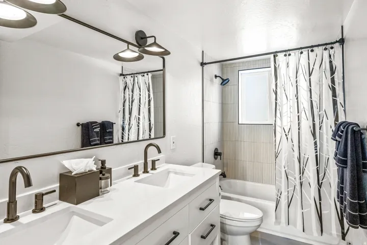 Bathroom featuring shower / tub combo with curtain and double vanity