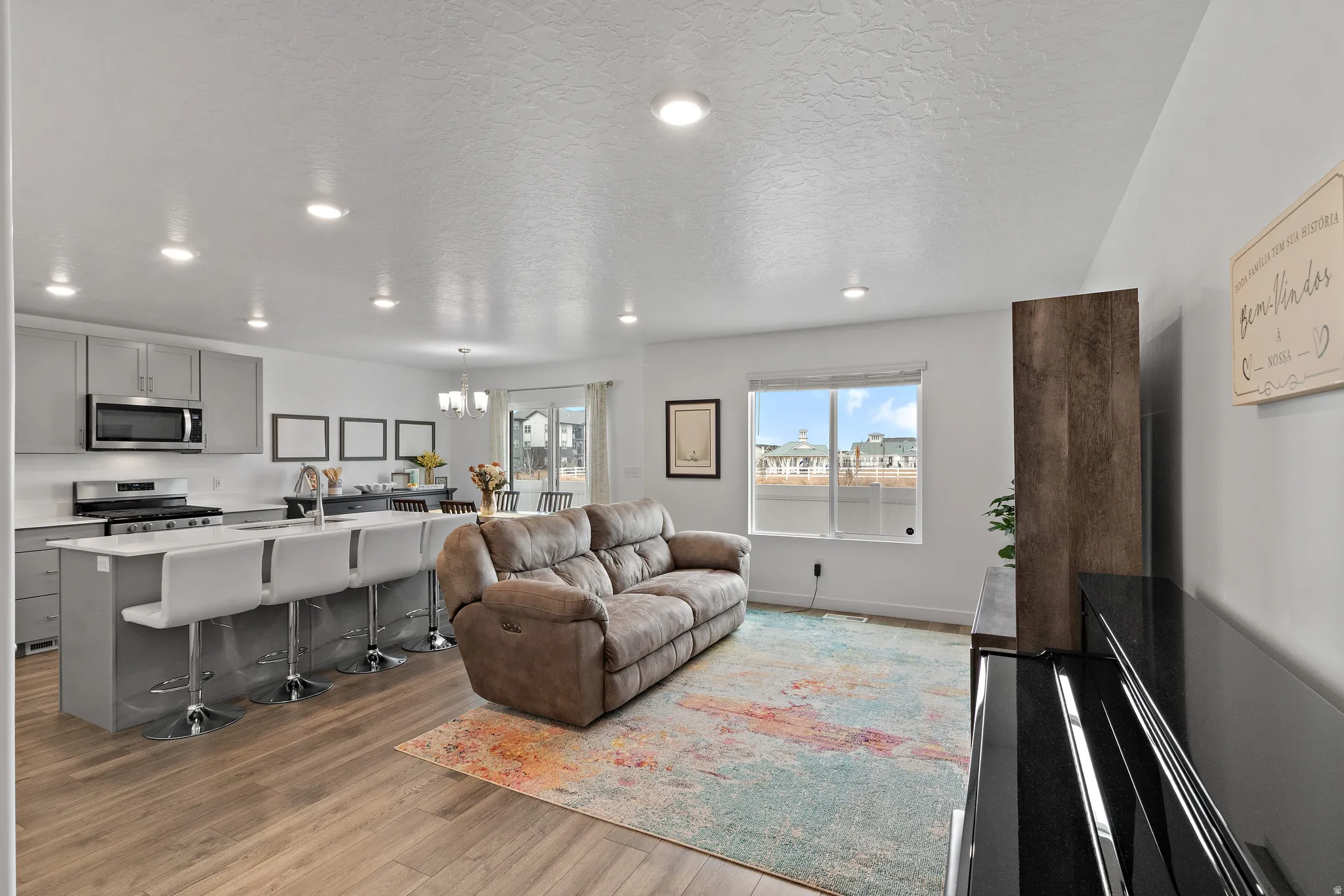 Living area featuring suspended lighting, light wood-style floors, and a textured ceiling