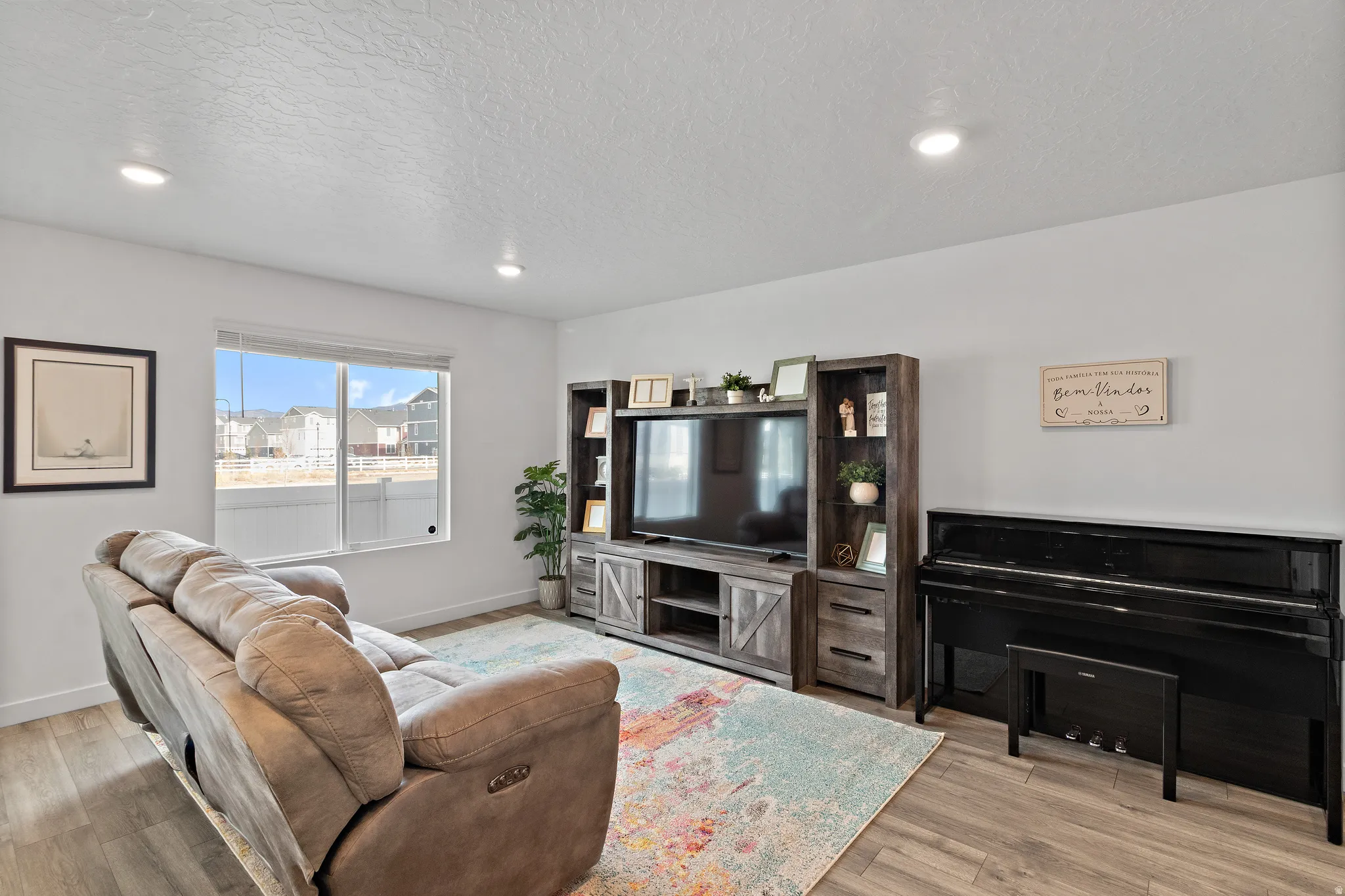 Living area with a textured ceiling, light wood finished floors, and recessed lighting