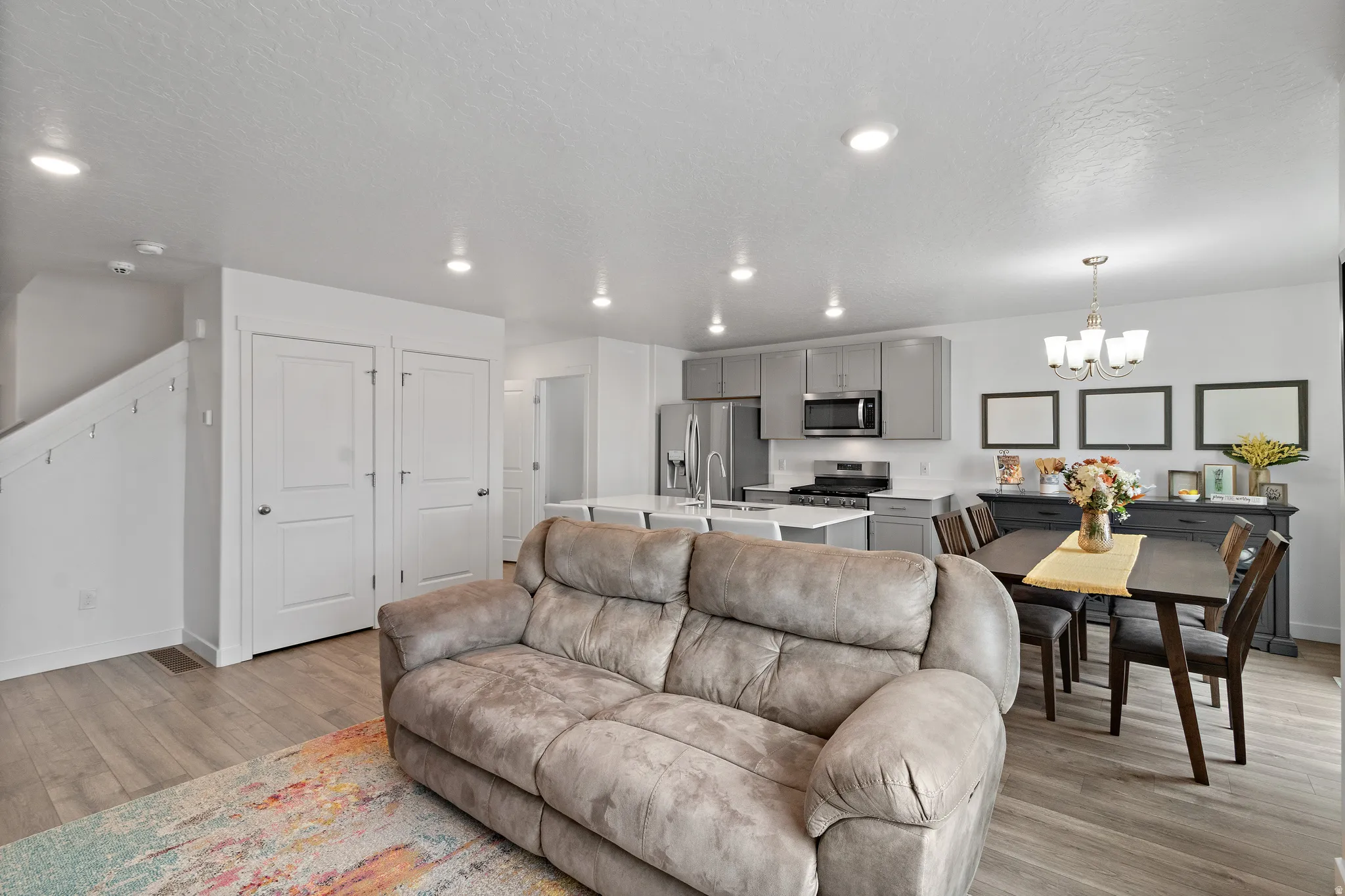 Living room with light wood finished floors, a chandelier, and a textured ceiling
