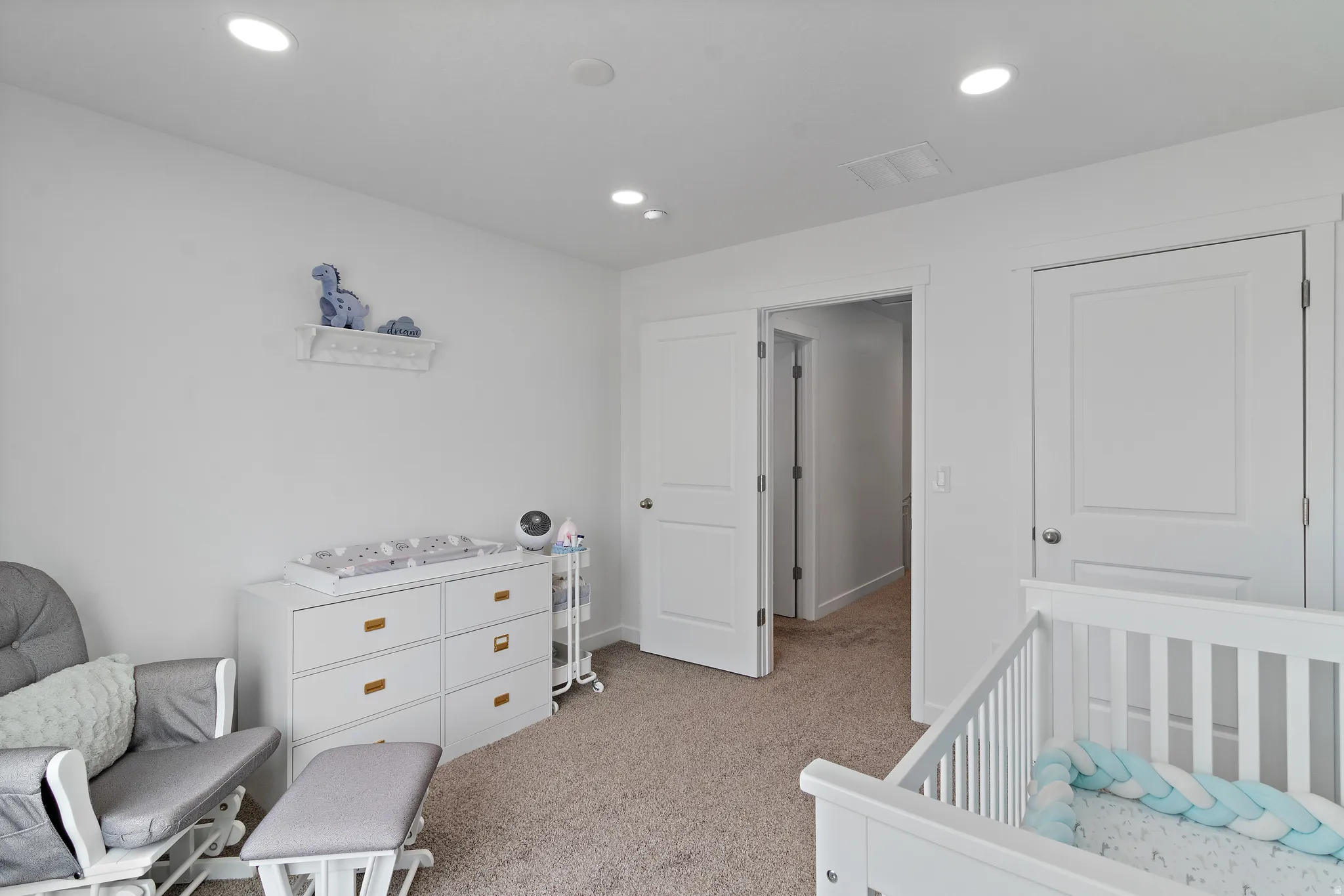 Bedroom featuring light carpet, a crib, and recessed lighting