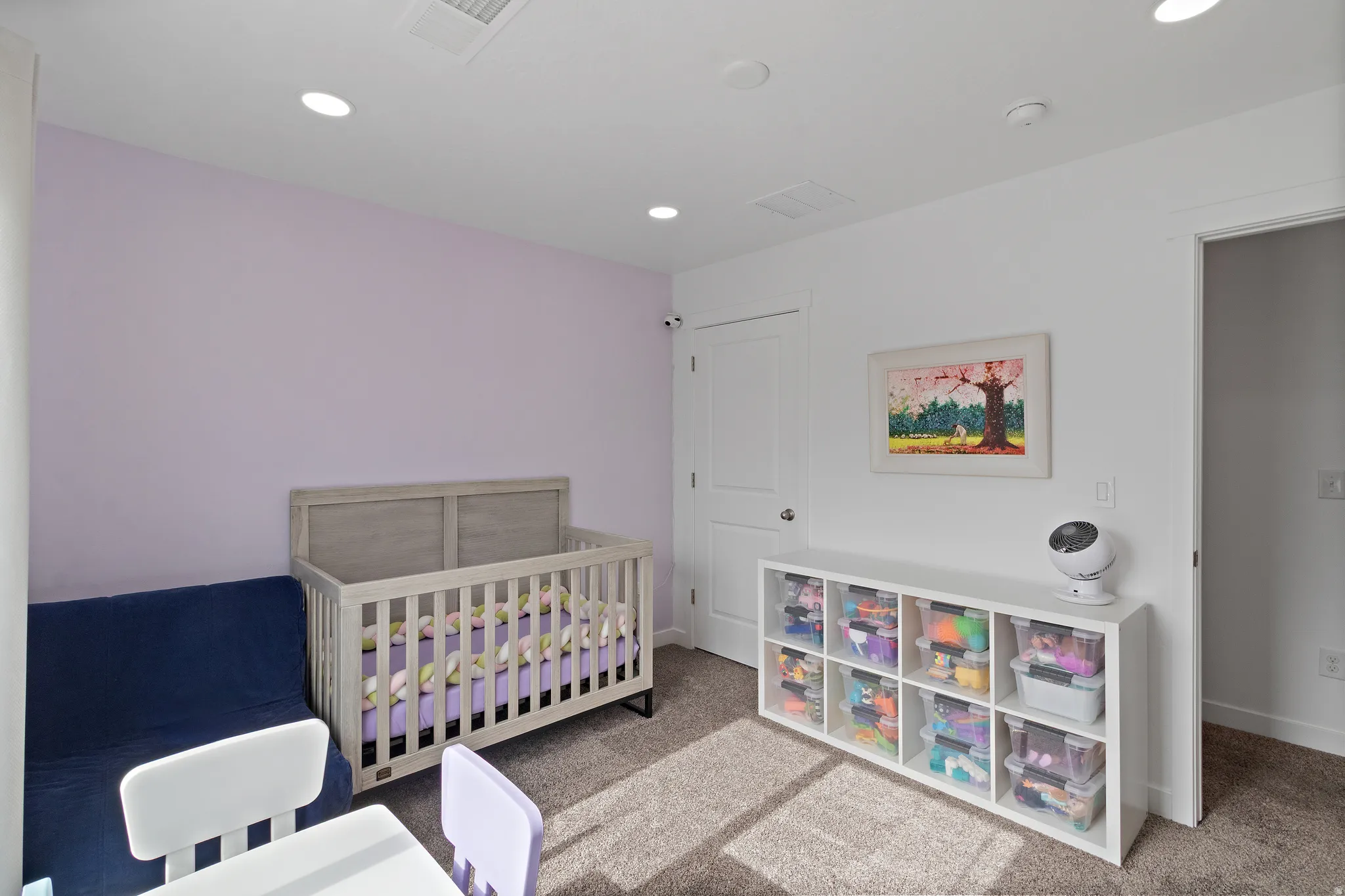 Carpeted bedroom with a crib and recessed lighting