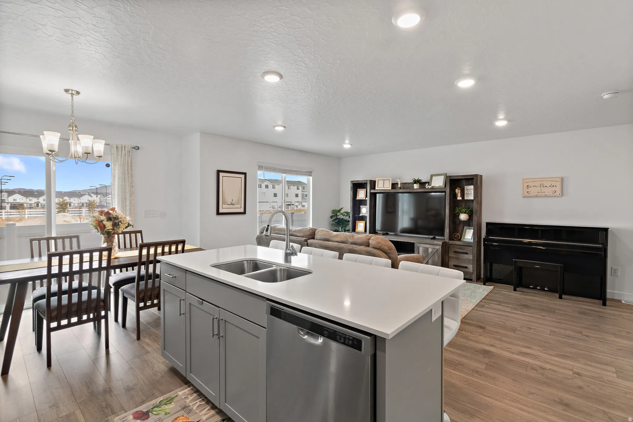 Kitchen with dishwasher, gray cabinetry, a center island with sink, open floor plan, and light wood finished floors