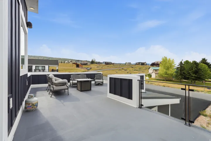 Expansive outdoor patio with a durable surface, dark paneling, and a clear glass and metal railing system