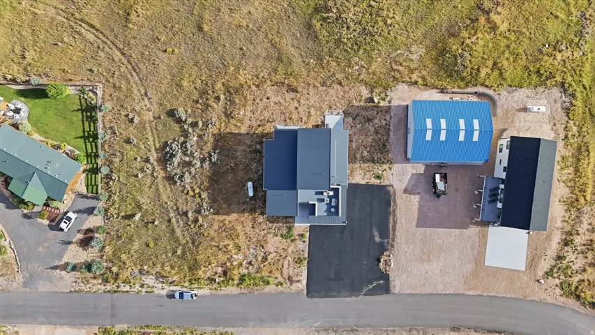 Expansive property featuring three distinct structures, an asphalt driveway, and a large gravel area
