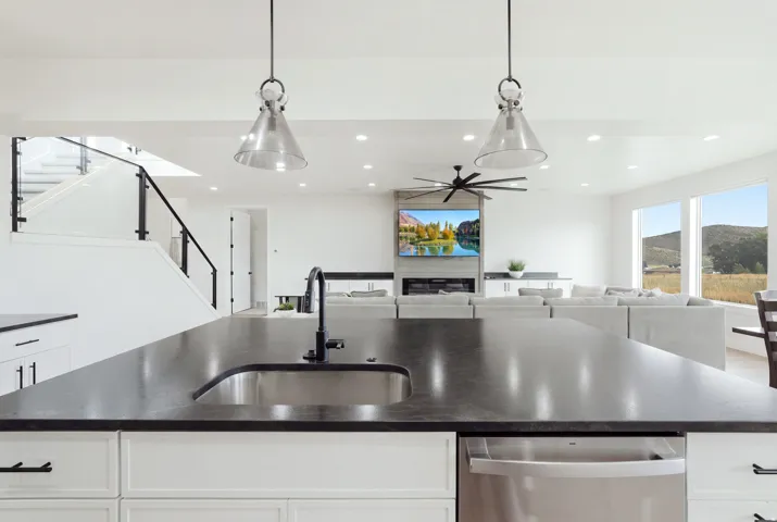 Expansive kitchen island with dark countertop, undermount sink, and matte black faucet
