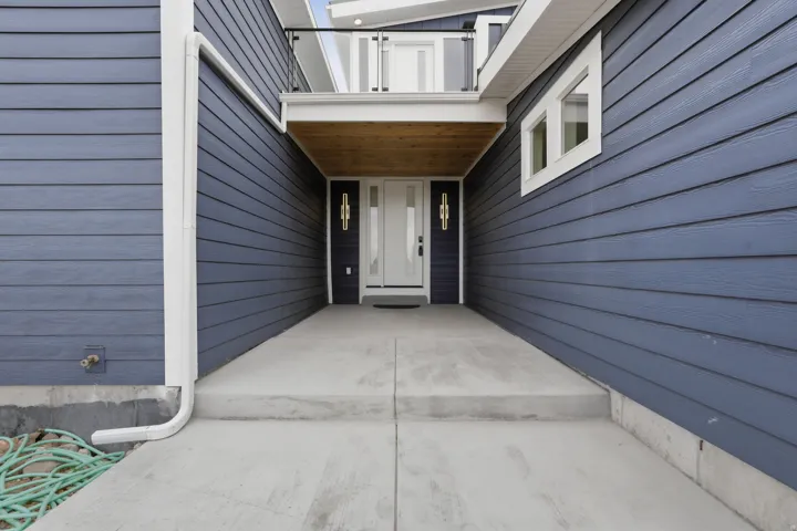 Entryway featuring concrete steps, blue horizontal siding, white trim windows, and two wall-mounted light fixtures framing the front door