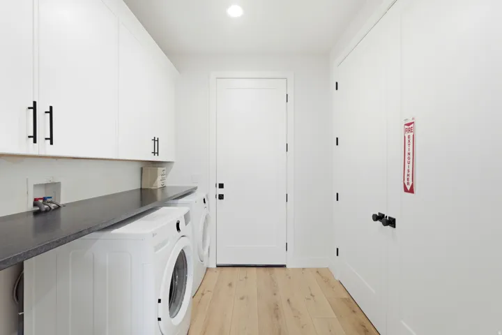 Light wood-finish flooring, white cabinetry with matte black hardware, and a dark countertop