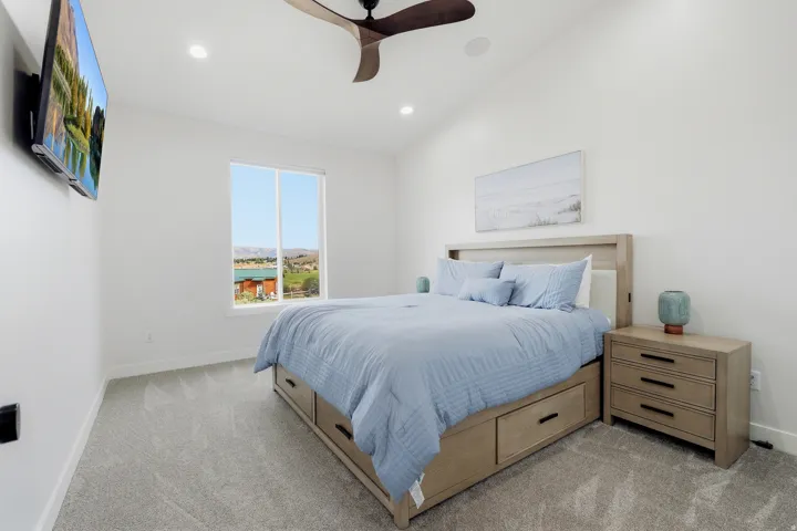 Vaulted ceiling with a ceiling fan, recessed lighting, and a large window