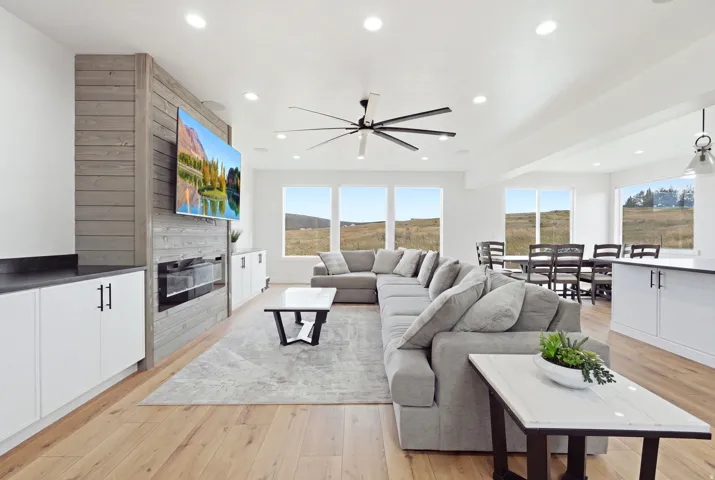 Open-concept living space featuring wood-finish flooring, a linear fireplace, and recessed lighting