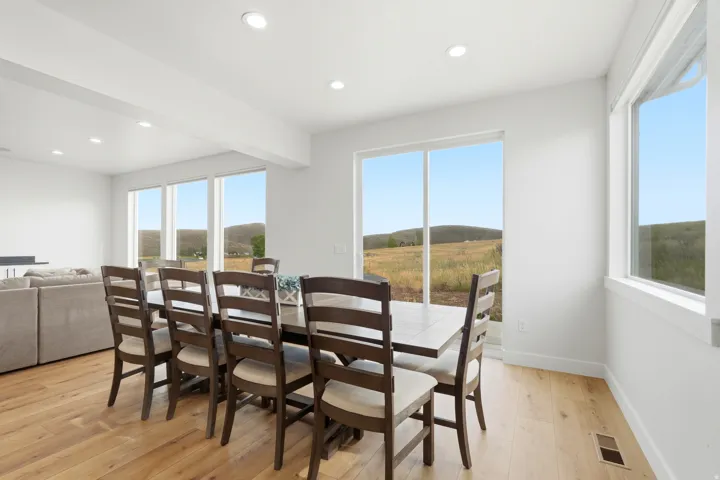 Open-concept living area with wood-finish flooring, recessed lighting, and expansive windows