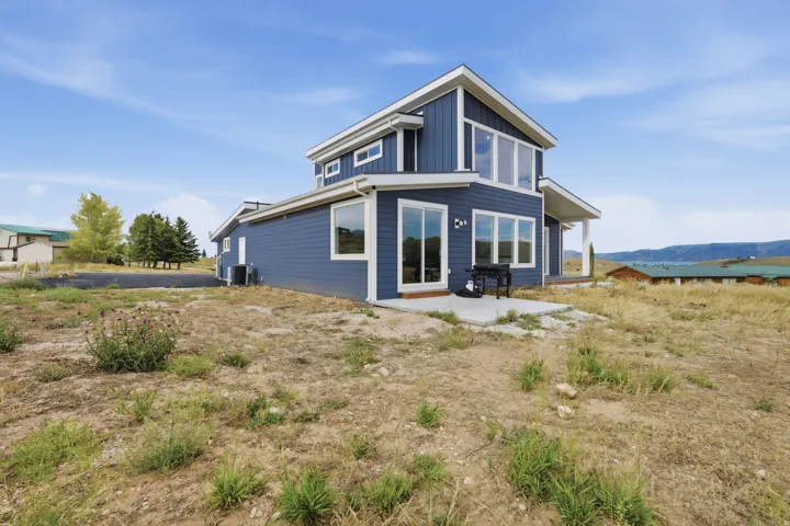 Modern siding exterior with multiple window styles, concrete patio, and sliding glass doors