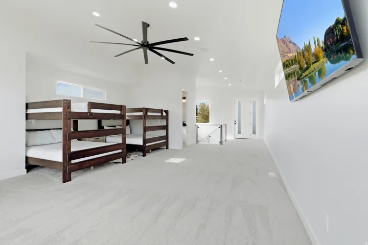 Spacious room featuring light-colored carpeting, recessed lighting, a large ceiling fan, and high ceilings