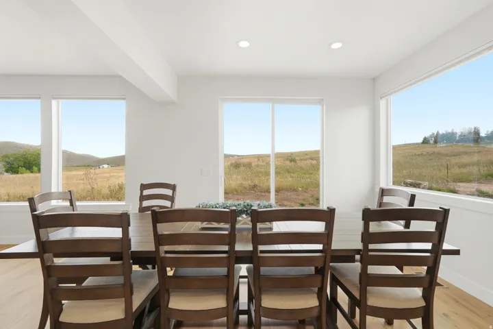 Recessed ceiling lighting, multiple large windows, light wood-finish flooring, and a spacious dining area