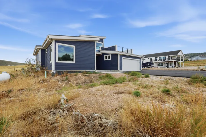 Modern exterior featuring dark blue siding, white trim, a single-car garage, and a flat roofline