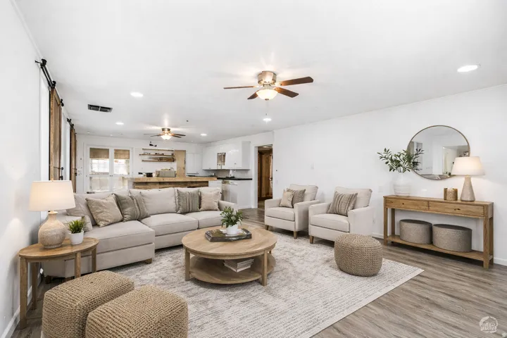 Living room with a ceiling fan, recessed lighting, light wood-style floors, and a barn door