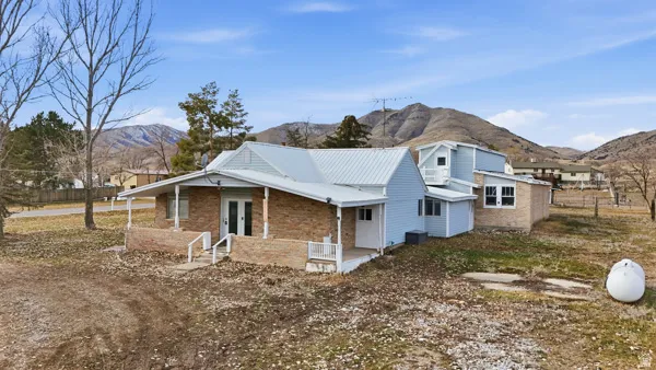 View of property exterior featuring covered porch, a mountain view, brick siding, double doors, and a metal roof