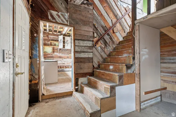 Staircase featuring wooden walls and concrete flooring