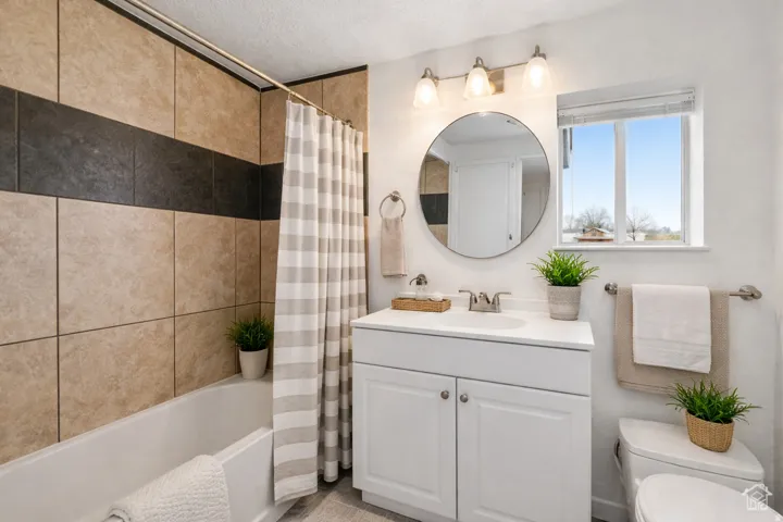 Bathroom with vanity, shower / tub combo with curtain, and a textured ceiling