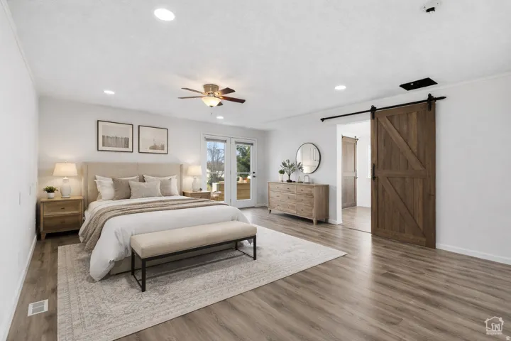 Bedroom with a barn door, access to exterior, wood finished floors, ceiling fan, and recessed lighting