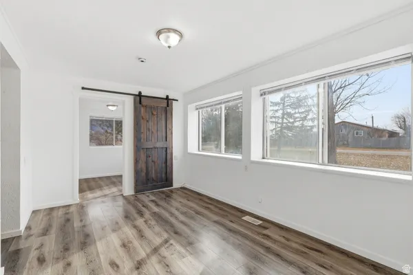 Unfurnished bedroom featuring a barn door, wood finished floors, and multiple windows