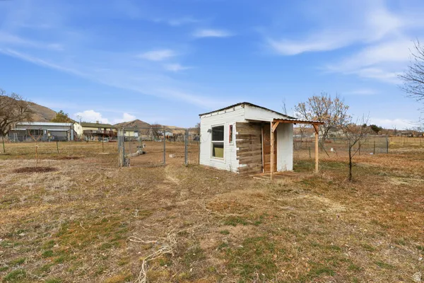 View of outdoor structure featuring a view of countryside and a gate. There are 2 plum, 2 apple, 2 pear and one cherry tree located on the property