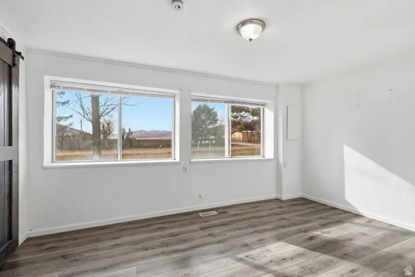 Empty room featuring a barn door and wood finished floors