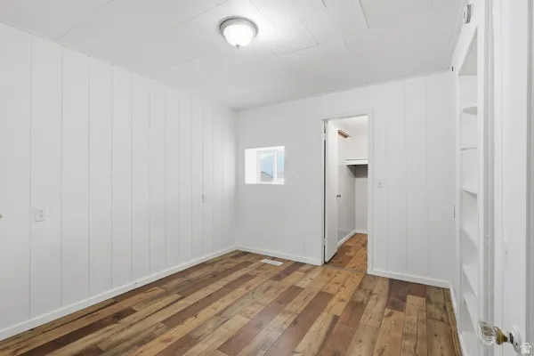 Unfurnished bedroom featuring hardwood / wood-style flooring and a walk in closet
