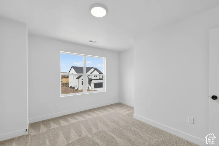 Empty room featuring light colored carpet and a textured ceiling